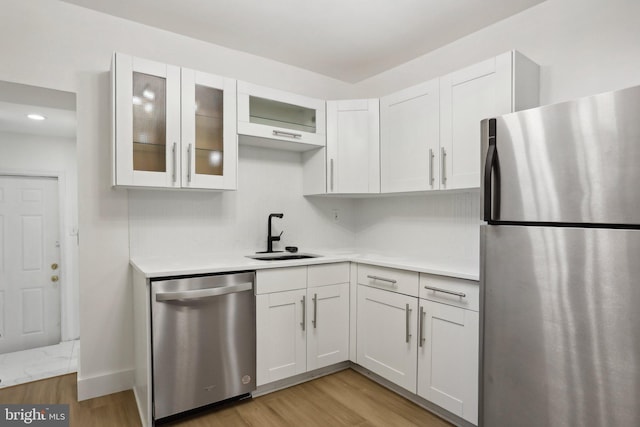 kitchen featuring sink, appliances with stainless steel finishes, light wood-type flooring, and white cabinetry