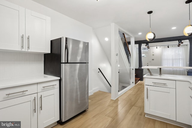 kitchen featuring white cabinetry, pendant lighting, light hardwood / wood-style flooring, and stainless steel fridge