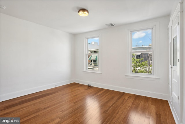 empty room with hardwood / wood-style flooring and a wealth of natural light