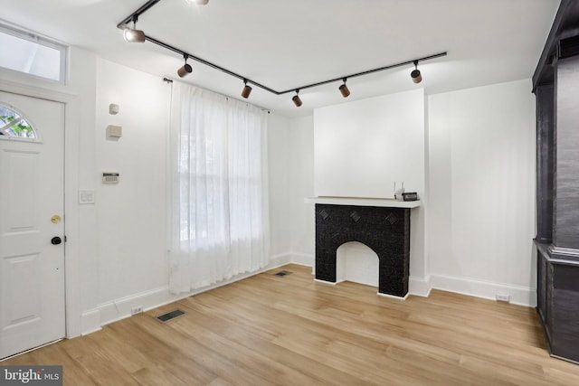 unfurnished living room featuring rail lighting and light wood-type flooring