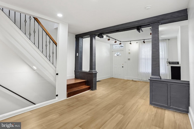 entryway featuring ornate columns, light wood-type flooring, and track lighting