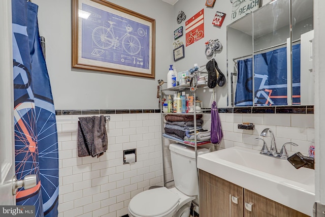 bathroom with vanity, toilet, and tile walls