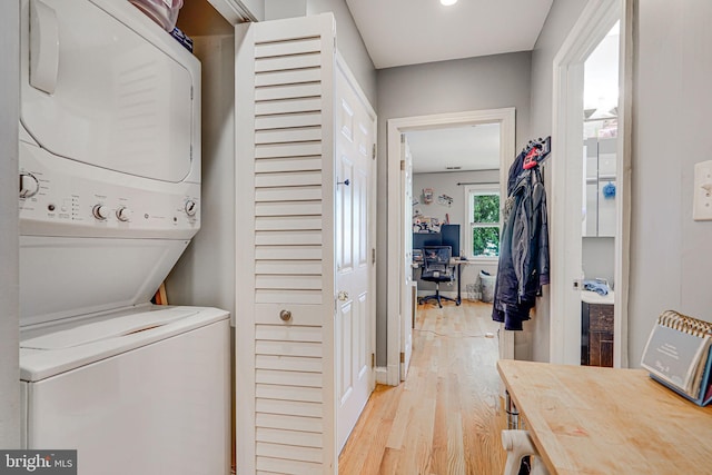 laundry room with light hardwood / wood-style floors and stacked washer and dryer