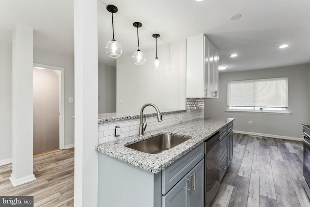 kitchen with light stone counters, pendant lighting, sink, and light wood-type flooring