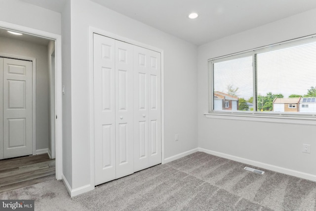 unfurnished bedroom with light colored carpet and a closet