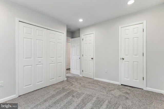 unfurnished bedroom featuring light colored carpet and two closets