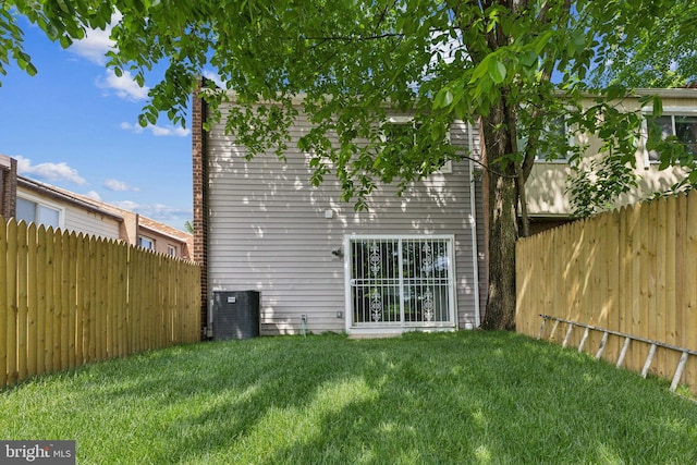 rear view of house featuring central AC and a lawn