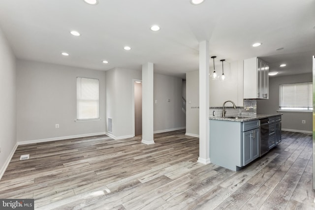 kitchen featuring light stone counters, light hardwood / wood-style flooring, backsplash, and hanging light fixtures