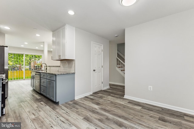 kitchen featuring light stone counters, white cabinets, sink, tasteful backsplash, and hardwood / wood-style floors