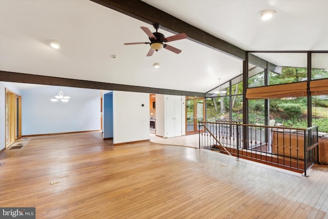 unfurnished living room with ceiling fan with notable chandelier, beamed ceiling, and light hardwood / wood-style flooring