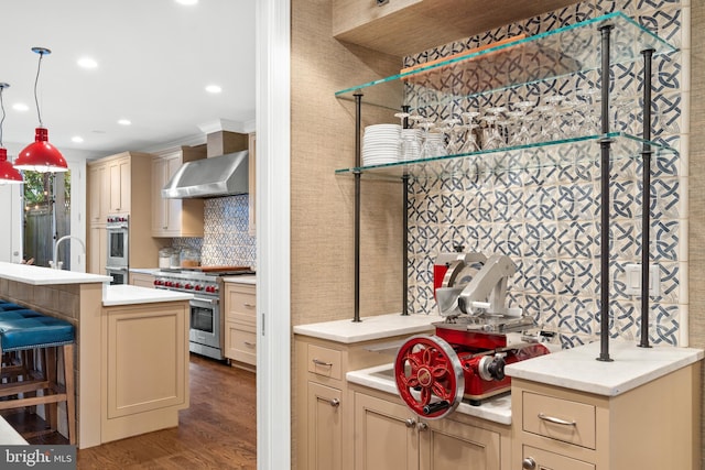 kitchen with a center island with sink, wall chimney range hood, crown molding, dark hardwood / wood-style floors, and stainless steel appliances