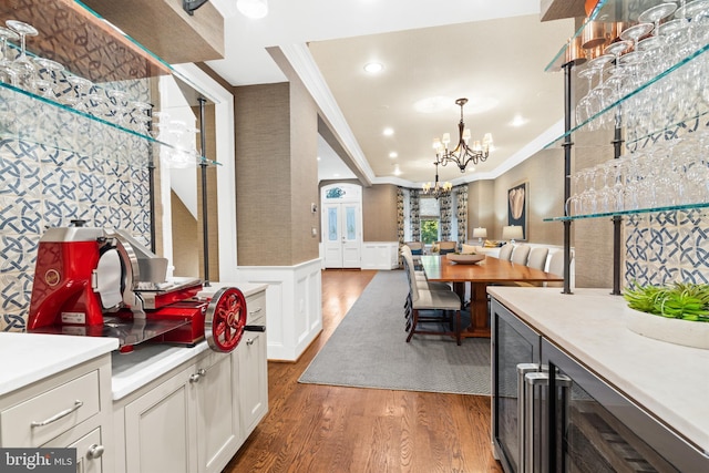 dining area featuring crown molding, wine cooler, bar, dark hardwood / wood-style flooring, and a chandelier