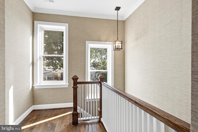 stairway featuring hardwood / wood-style floors, crown molding, and a notable chandelier