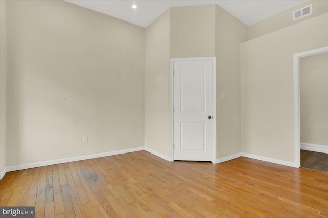 unfurnished room featuring lofted ceiling and light hardwood / wood-style floors