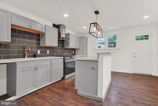 kitchen featuring gray cabinets, stainless steel stove, dark hardwood / wood-style floors, wall chimney range hood, and a center island