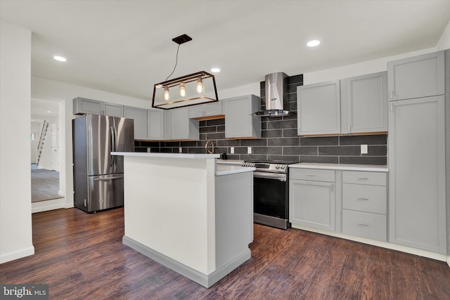 kitchen with wall chimney exhaust hood, a kitchen island, tasteful backsplash, dark wood-type flooring, and stainless steel appliances