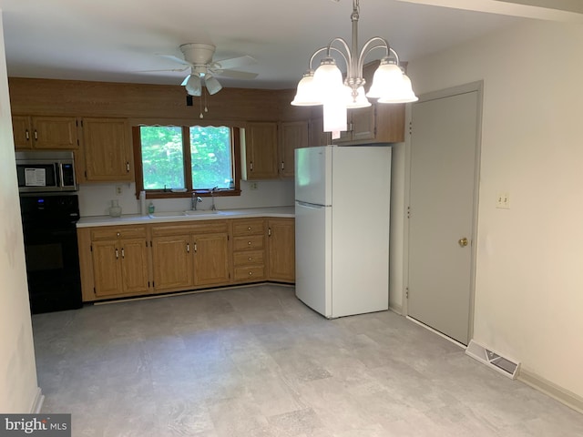 kitchen featuring white fridge, pendant lighting, stove, ceiling fan with notable chandelier, and sink