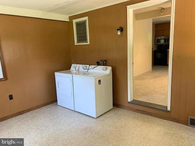 clothes washing area featuring wooden walls, hookup for a washing machine, and washer and clothes dryer