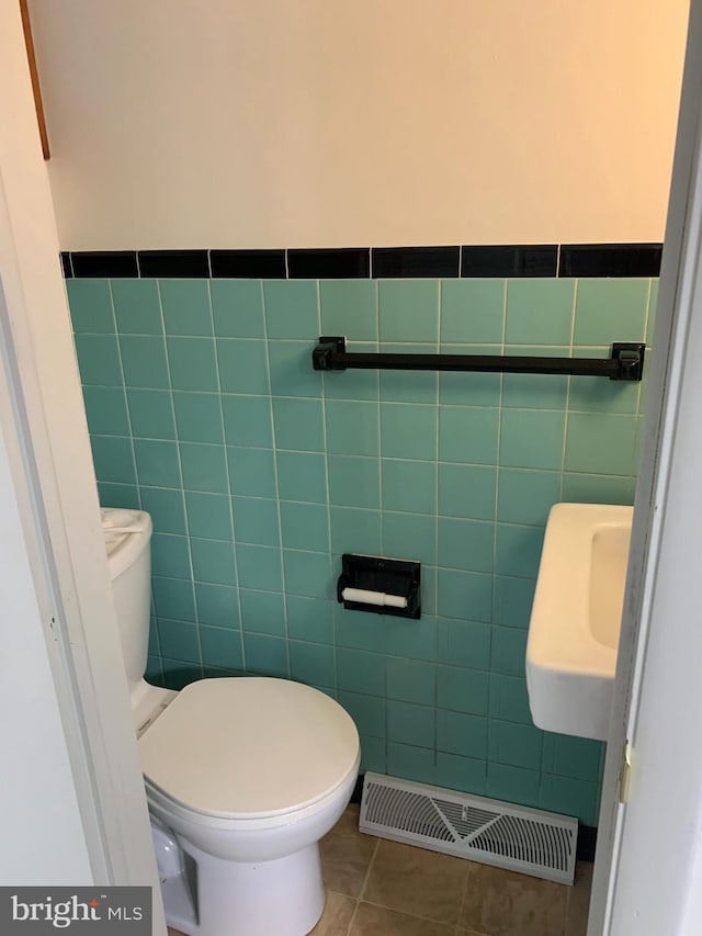 bathroom featuring tile floors, sink, toilet, and tile walls