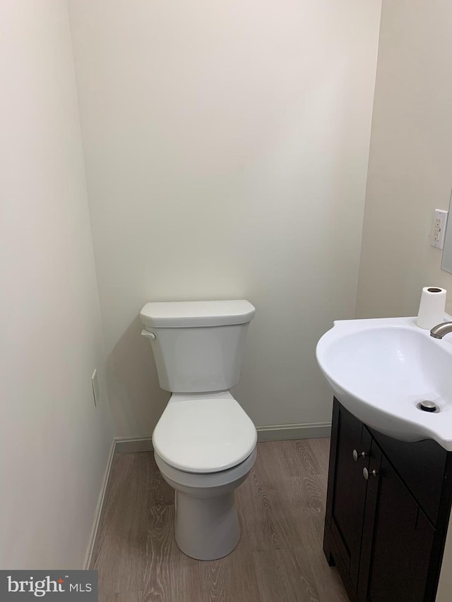 bathroom with wood-type flooring, vanity, and toilet