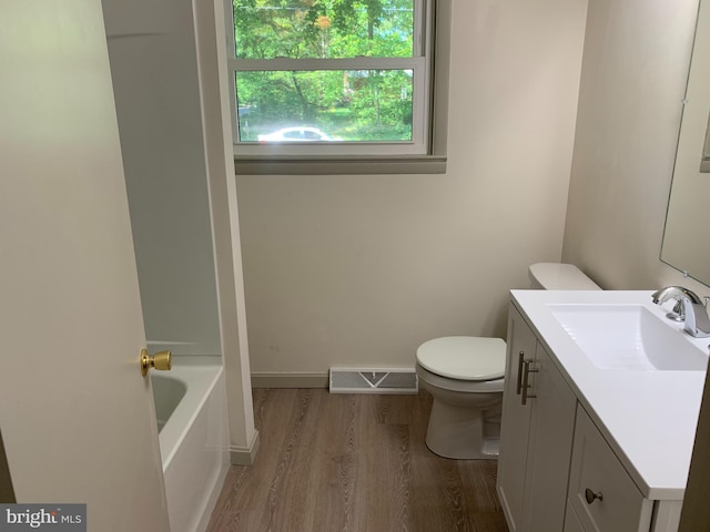 full bathroom featuring hardwood / wood-style floors, vanity, toilet, and shower / tub combination