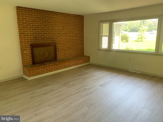 unfurnished living room with brick wall, wood-type flooring, and a fireplace