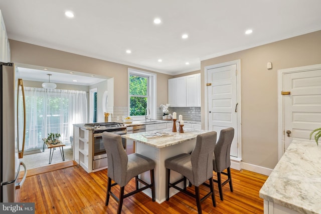 dining space with crown molding, sink, and light hardwood / wood-style flooring