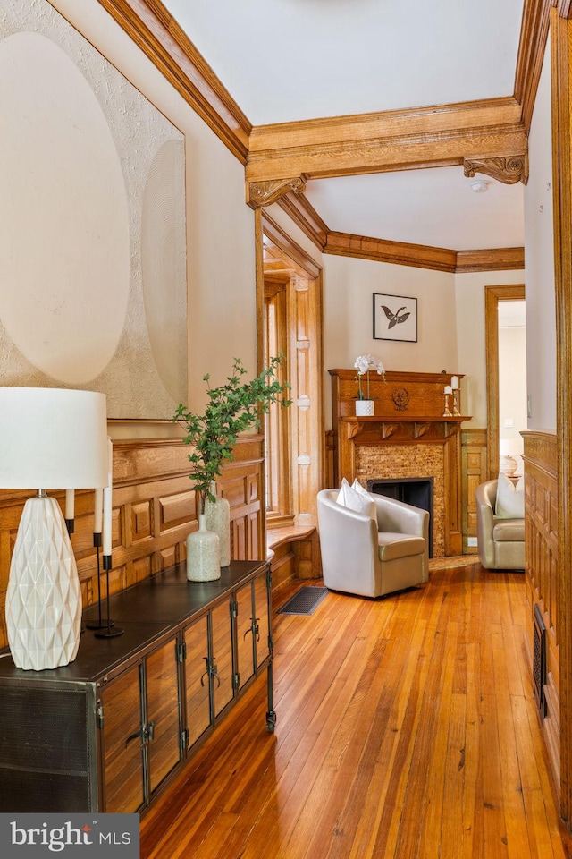 living room featuring a stone fireplace, wood-type flooring, and ornamental molding