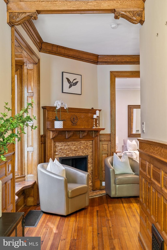 living area with a fireplace, wood-type flooring, and ornamental molding