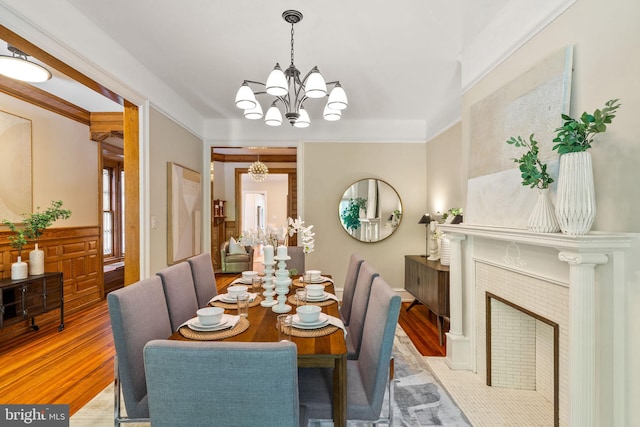 dining room featuring crown molding, a fireplace, light hardwood / wood-style floors, and an inviting chandelier