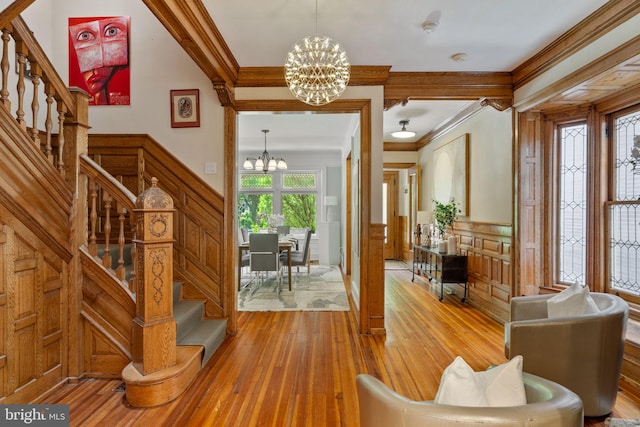 foyer entrance with a chandelier, light wood-type flooring, and ornamental molding