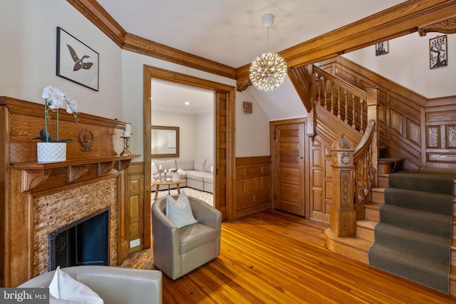 sitting room with crown molding, a chandelier, a fireplace, and hardwood / wood-style floors