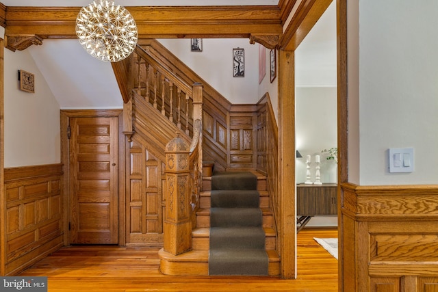 staircase featuring hardwood / wood-style flooring, vaulted ceiling with beams, and a chandelier