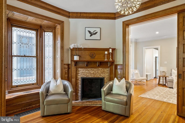 living area featuring a tile fireplace, a wealth of natural light, an inviting chandelier, and hardwood / wood-style flooring