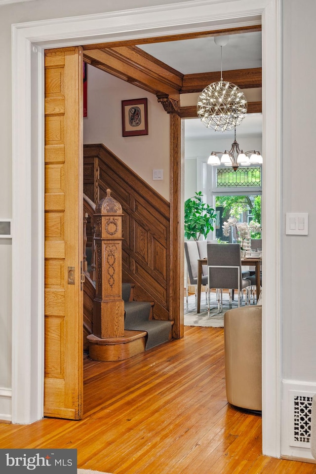 stairs with hardwood / wood-style floors and an inviting chandelier