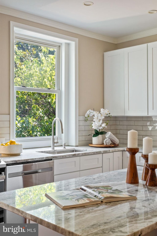 kitchen with backsplash, white cabinetry, sink, and light stone counters