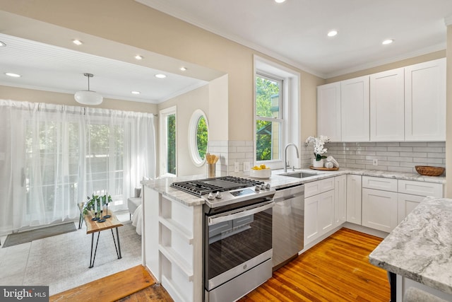 kitchen featuring appliances with stainless steel finishes, tasteful backsplash, sink, light hardwood / wood-style flooring, and white cabinetry