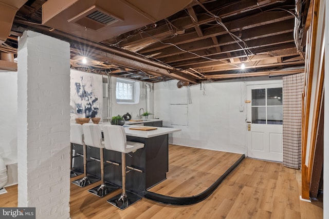 basement featuring light hardwood / wood-style floors and sink