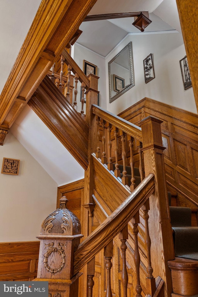 staircase featuring lofted ceiling and wooden walls