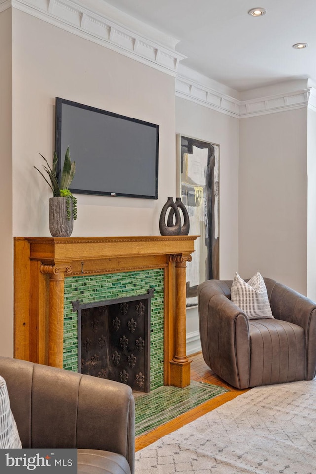 living room with a tile fireplace, hardwood / wood-style flooring, and ornamental molding