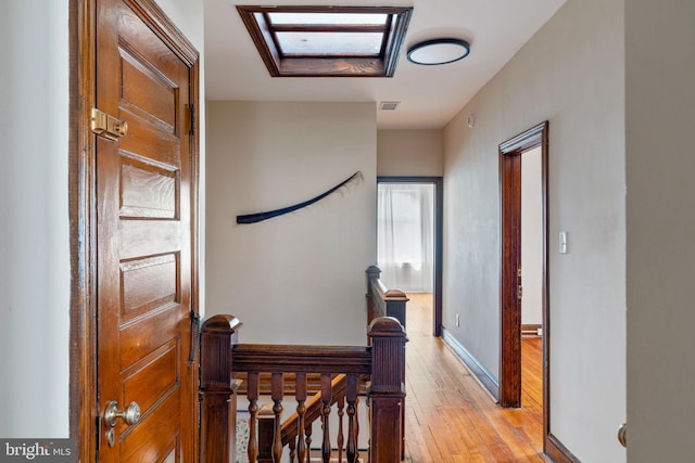 hallway featuring light hardwood / wood-style floors and a skylight