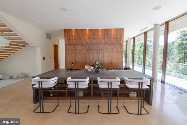 dining space with breakfast area, a wall of windows, and wood walls