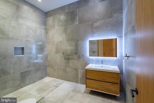 bathroom with vanity, tile walls, and walk in shower