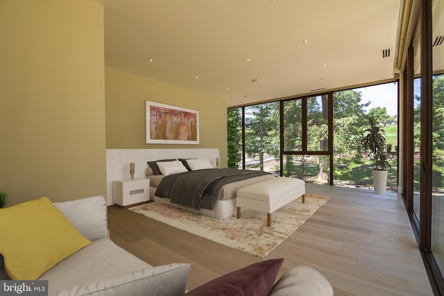 bedroom with expansive windows and light wood-type flooring