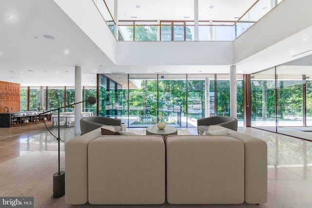 unfurnished living room with a wealth of natural light, a towering ceiling, and light tile patterned floors