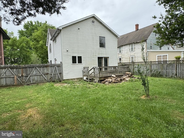 rear view of house with a wooden deck and a lawn