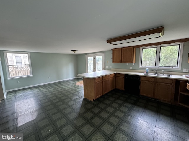 kitchen with black dishwasher, a healthy amount of sunlight, dark tile flooring, and sink