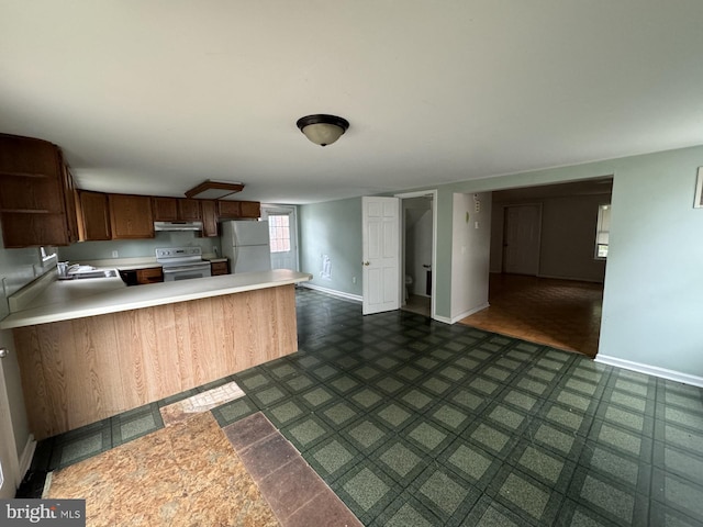 kitchen with dark tile floors, kitchen peninsula, white fridge, sink, and electric stove