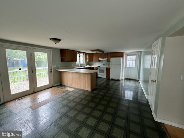 kitchen featuring kitchen peninsula, dark tile floors, and white appliances