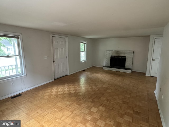 unfurnished living room featuring light parquet floors and a fireplace